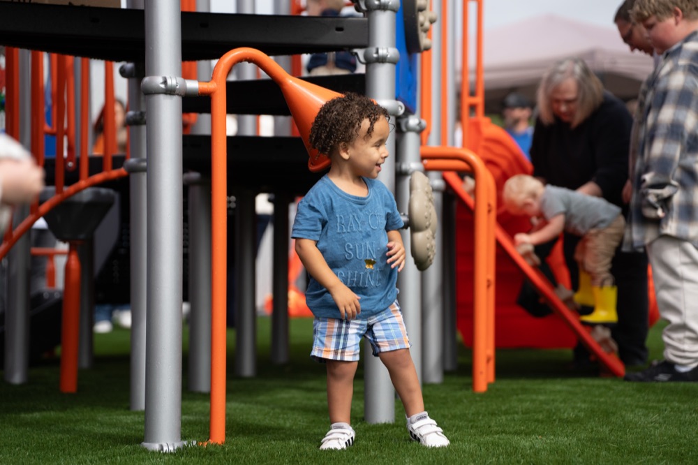 A young boy exploring under the orange play structure